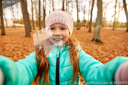 Image of happy girl taking selfie at autumn park