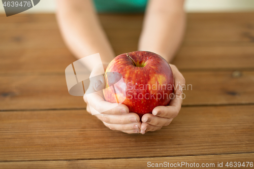 Image of close up of hands holding ripe red apple