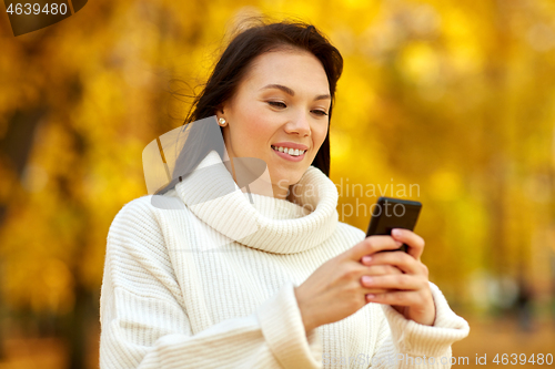 Image of woman with smartphone in autumn park