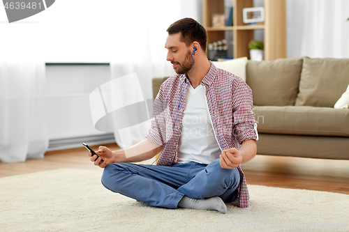 Image of man in earphones listening to music and meditating