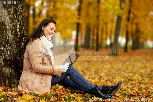 Image of woman with tablet computer at autumn park