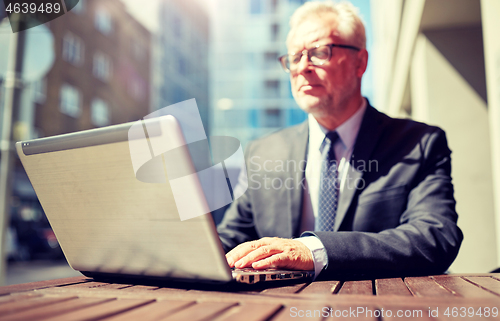 Image of senior businessman with laptop at outdoor cafe