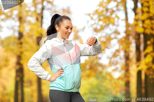 Image of woman looking at fitness tracker in autumn park