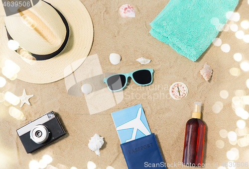 Image of travel tickets, camera and hat on beach sand