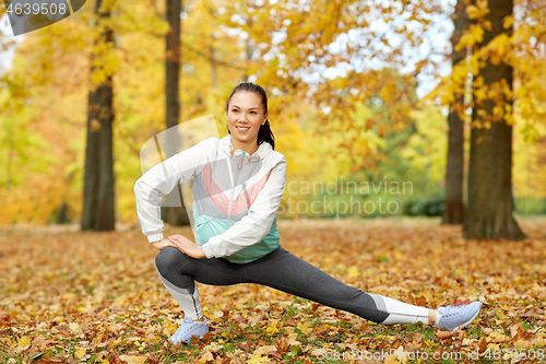 Image of young woman doing sports at autumn park