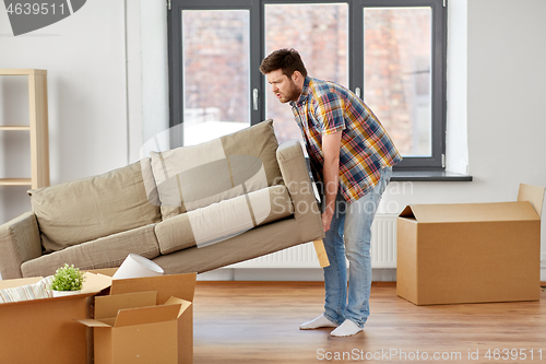 Image of man moving sofa at new home