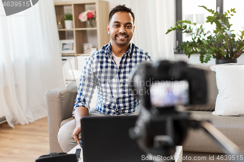 Image of male blogger with camera videoblogging at home