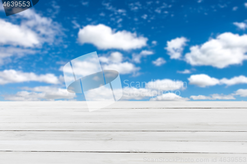 Image of Blank grey wooden table for display or montage your products on a blurred blue cloudy sky background.