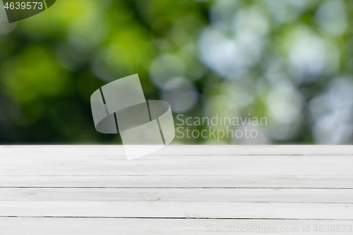 Image of Old wooden light grey table for display or montage your products on a green leaves blurred background.