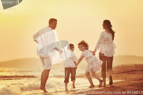 Image of happy young family have fun on beach at sunset