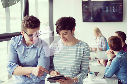 Image of Two Business People Working With Tablet in office