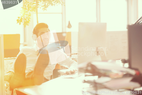 Image of relaxed young businessman first at workplace at early morning