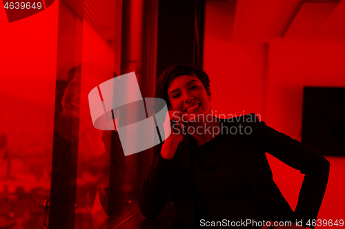 Image of Elegant Woman Using Mobile Phone by window in office building