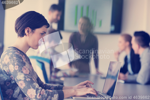 Image of young business woman at office working on laptop with team on me