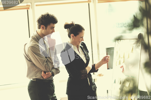 Image of young couple working on flip board at office