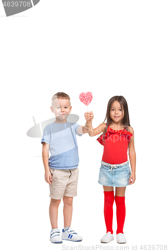 Image of Full length portrait of cute little kids in stylish clothes looking at camera and smiling with candy