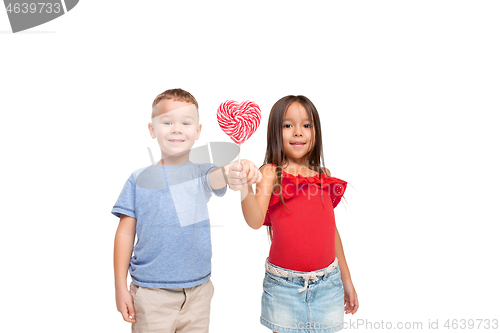 Image of Full length portrait of cute little kids in stylish clothes looking at camera and smiling with candy