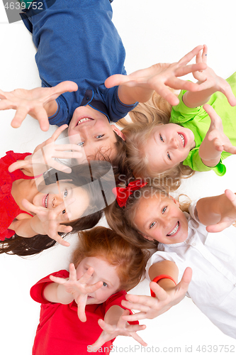 Image of Close-up of happy children lying on floor in studio and looking up