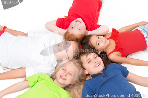 Image of Close-up of happy children lying on floor in studio and looking up