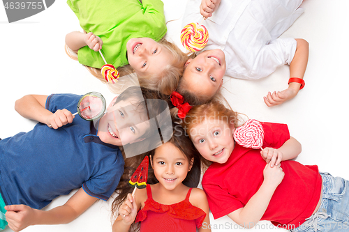 Image of Close-up of happy children lying on floor in studio and looking up