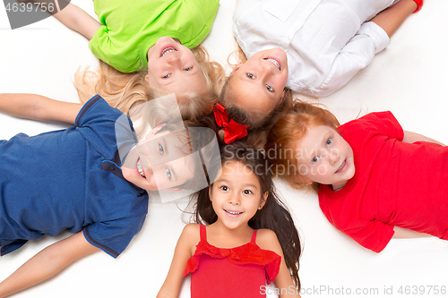 Image of Close-up of happy children lying on floor in studio and looking up