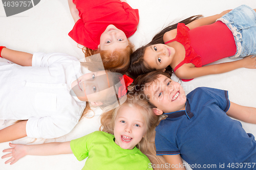 Image of Close-up of happy children lying on floor in studio and looking up