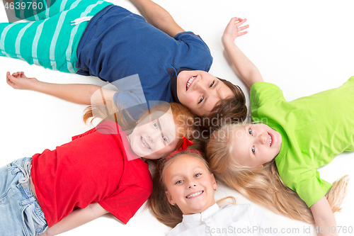 Image of Close-up of happy children lying on floor in studio and looking up