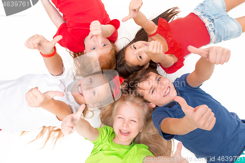 Image of Close-up of happy children lying on floor in studio and looking up