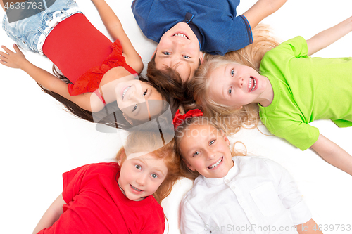 Image of Close-up of happy children lying on floor in studio and looking up