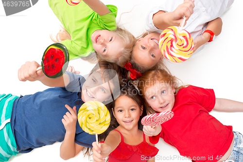 Image of Close-up of happy children lying on floor in studio and looking up