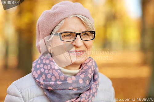 Image of portrait of happy senior woman at autumn park