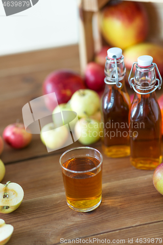 Image of glass and bottles of apple juice on wooden table