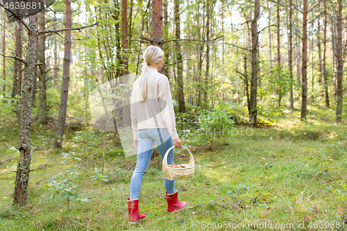 Image of young woman picking mushrooms in autumn forest