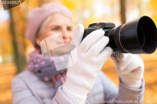 Image of senior woman with photo camera at autumn park