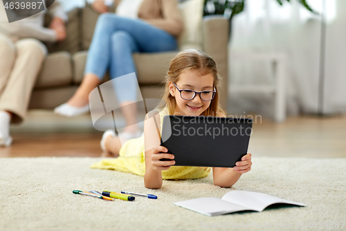 Image of student girl with tablet pc lying on floor at home