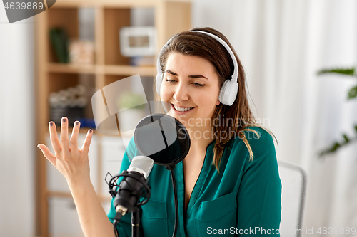 Image of woman with microphone recording podcast at studio