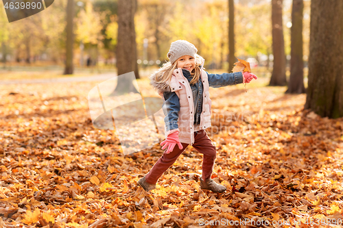 Image of happy girl running with maple leaf at autumn park