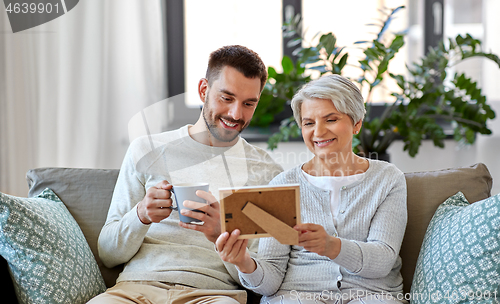 Image of adult son and senior mother with photo at home