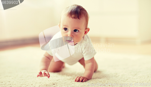 Image of little baby in diaper crawling on floor at home