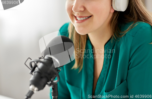 Image of woman with microphone recording podcast at studio