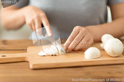 Image of woman cutting champignons by knife on board