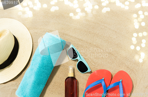 Image of straw hat, flip flops and sunglasses on beach sand