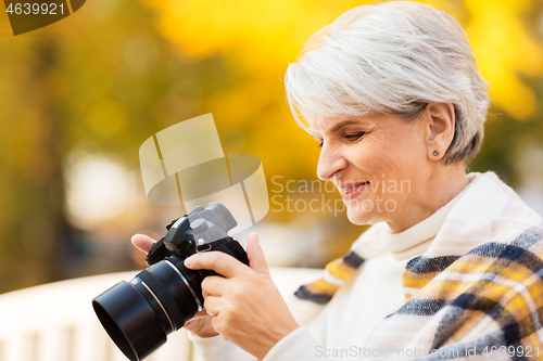 Image of senior woman with photo camera at autumn park