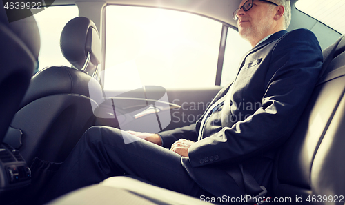 Image of senior businessman driving on car back seat