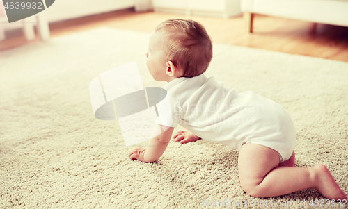 Image of little baby in diaper crawling on floor at home