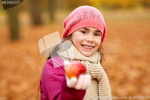 Image of happy girl with apple at autumn park