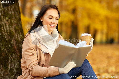 Image of woman reading book with coffee in autumn park