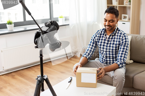 Image of male video blogger opening parcel box at home