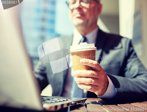 Image of senior businessman with laptop and coffee outdoors