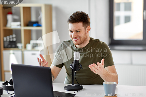 Image of man with laptop and microphone at home office